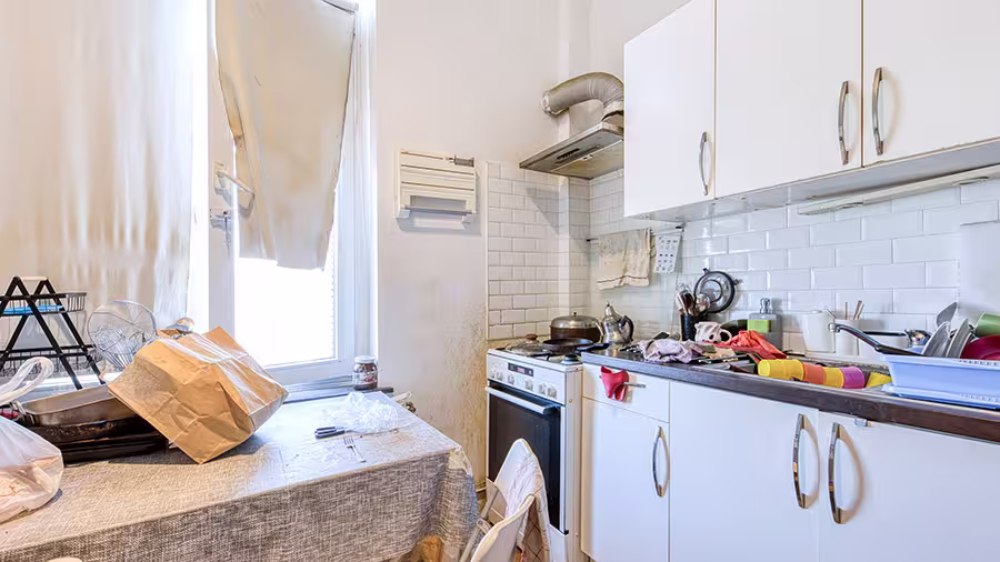 Cuisine étroite avec vaisselle, sacs et objets sur la table et le plan de travail